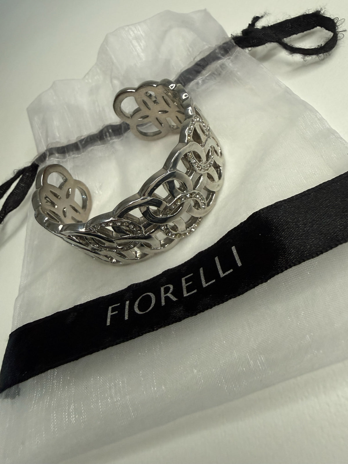Style Reset Fiorelli silver-tone wide cuff bracelet with interlocking circular pattern and crystal accents in pouch