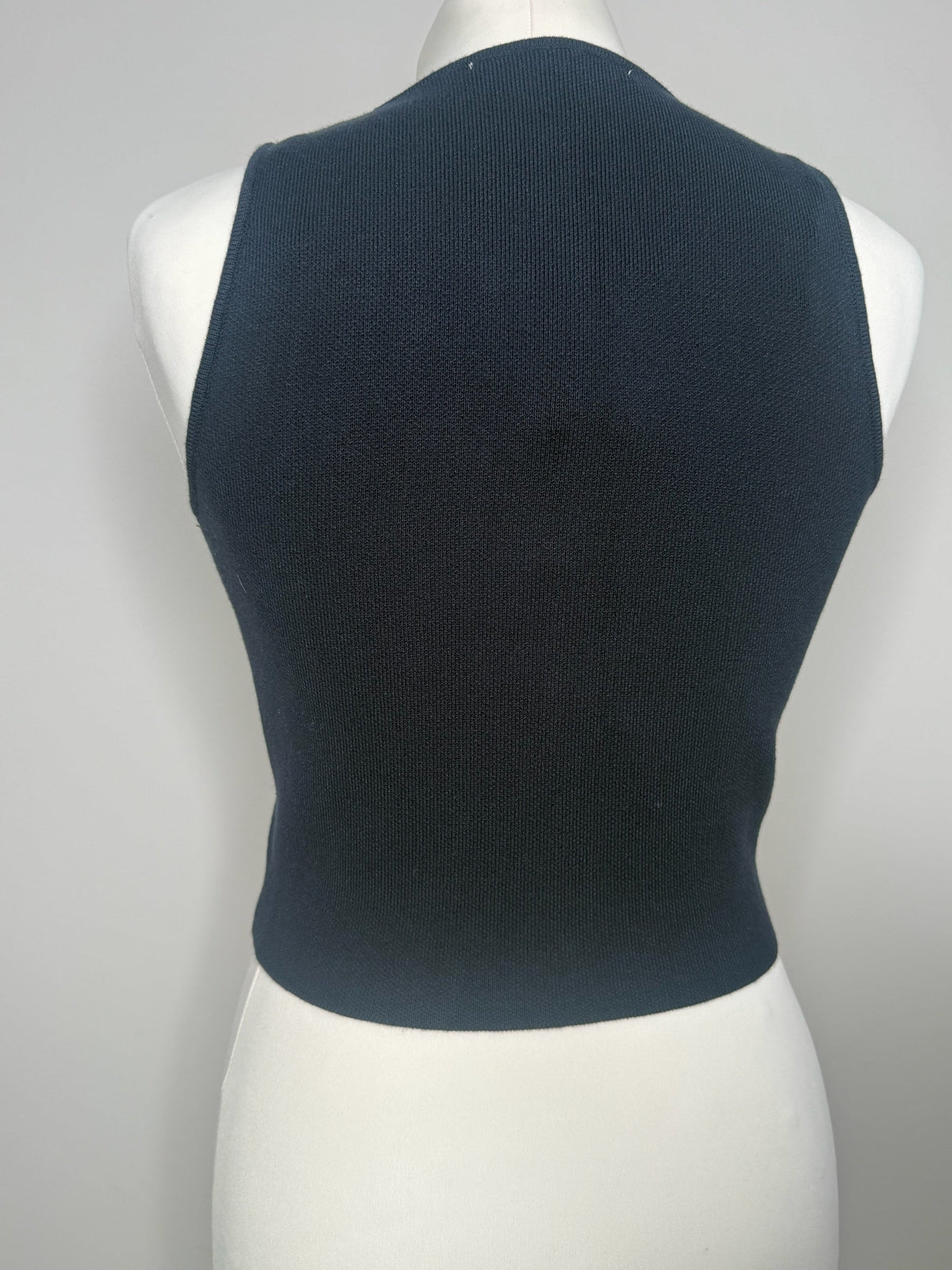 Style Reset navy blue sleeveless knit top on a mannequin, showing the plain back view of the fitted garment.