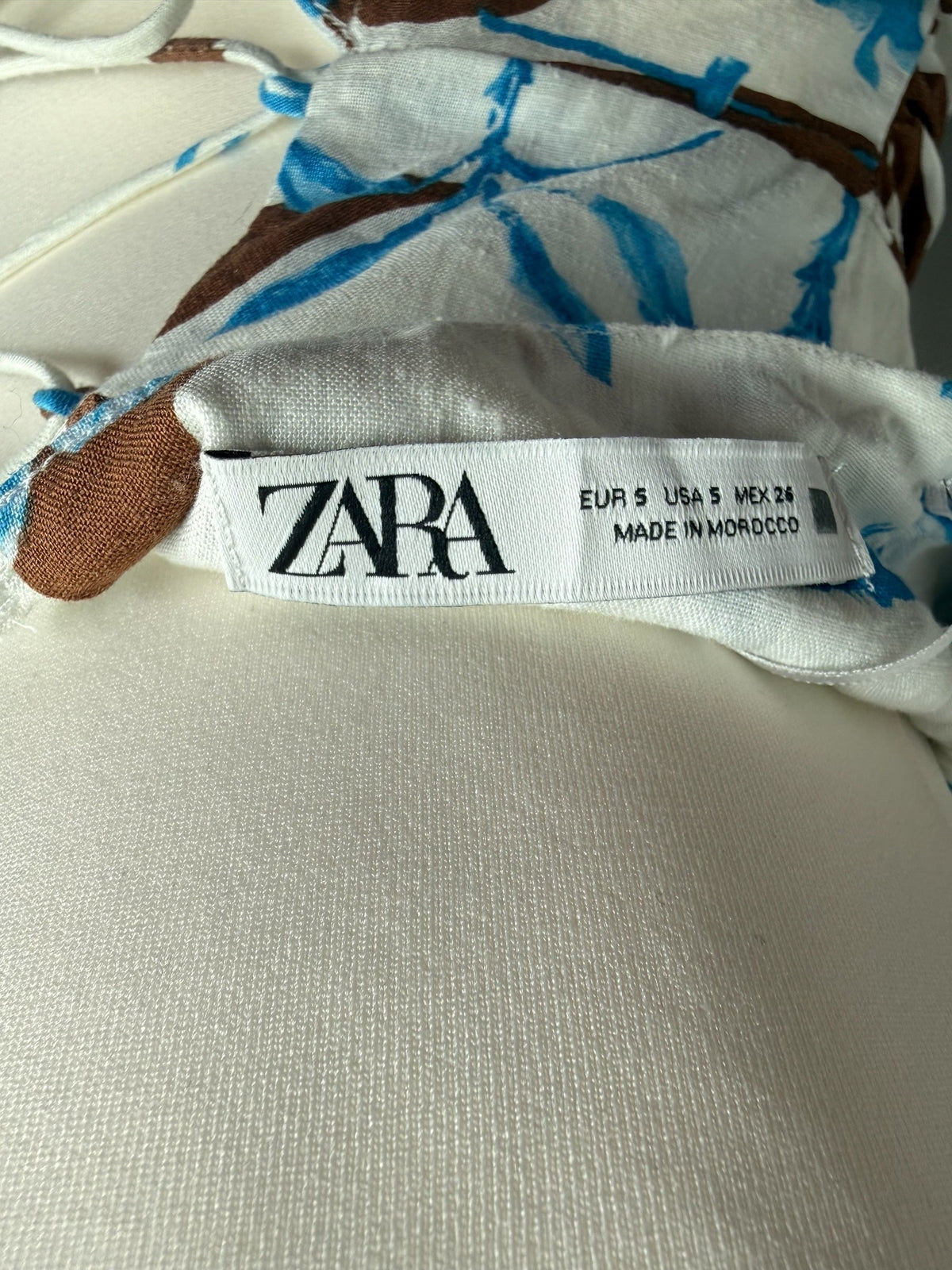 Style Reset ZARA floral print mini dress label showing size small and Moroccan origin on a white fabric background