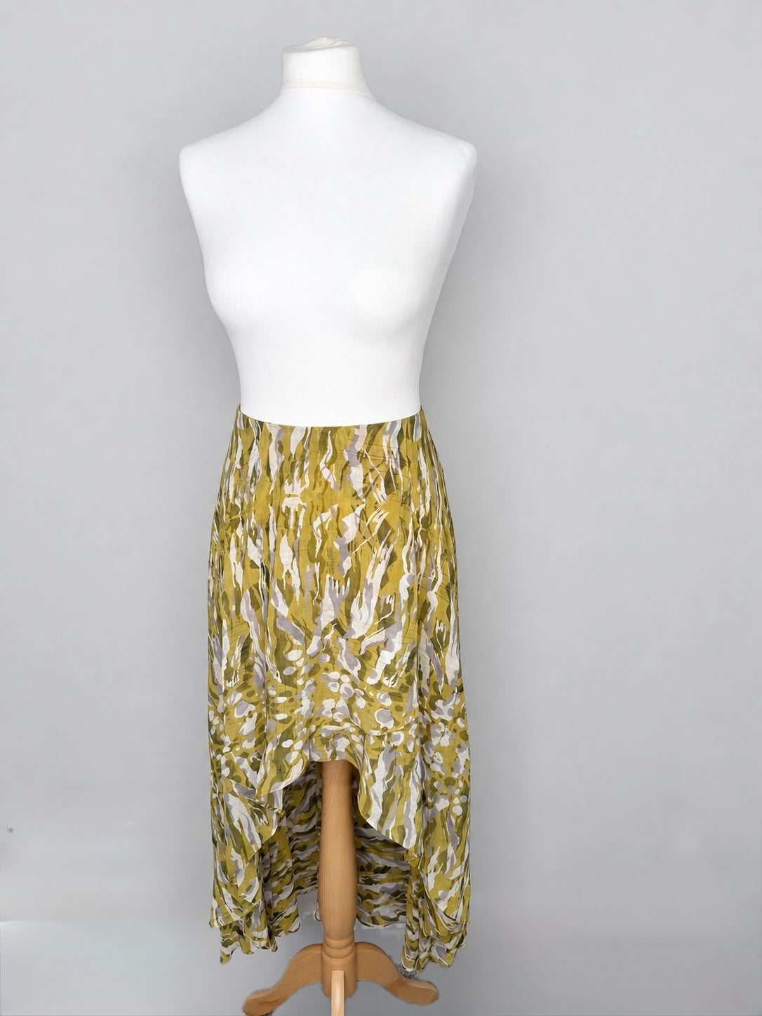 Style Reset ALLSAINTS high-low maxi skirt in olive, mustard, and grey abstract camouflage print on a mannequin.