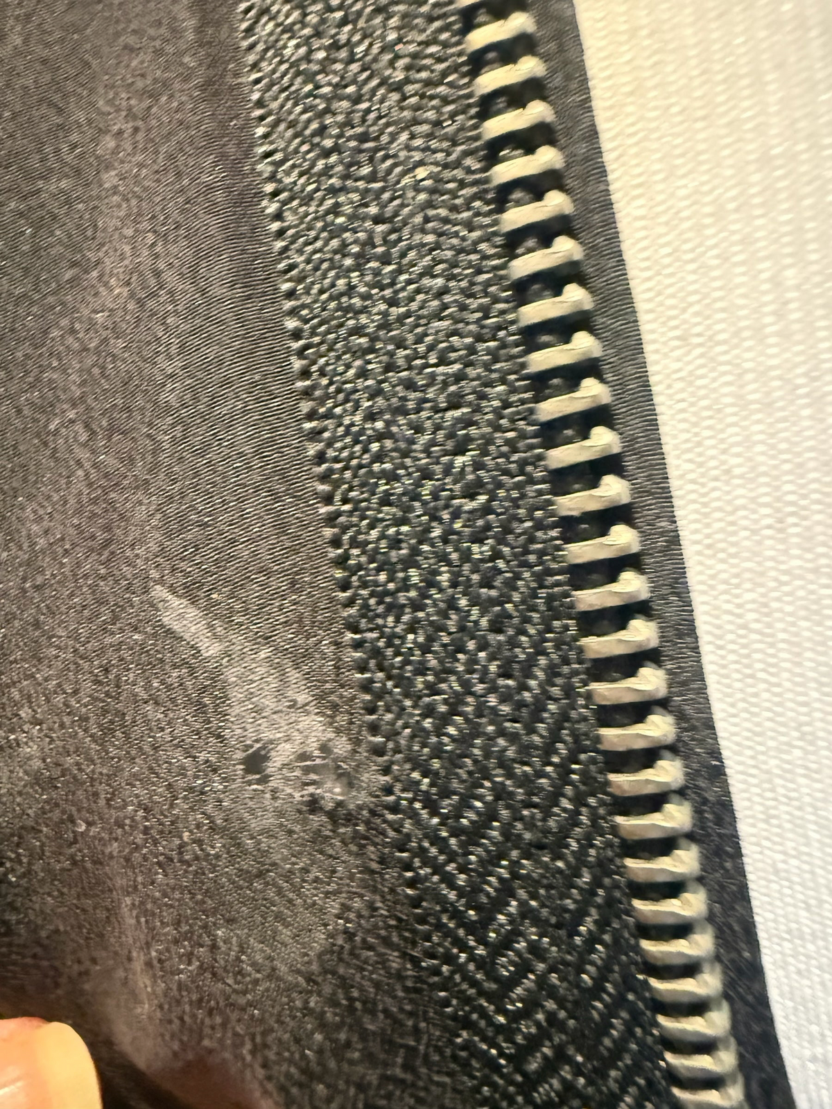Close-up of the black silk fabric and industrial metal zip detail on the Style Reset AllSaints midi dress
