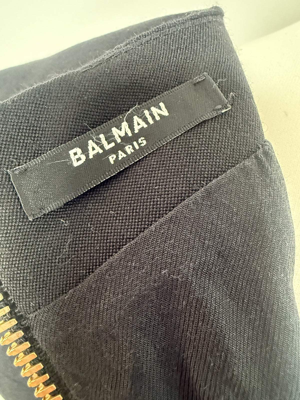 Style Reset Balmain Paris black mini dress label detail with gold tone zip hardware on textured fabric