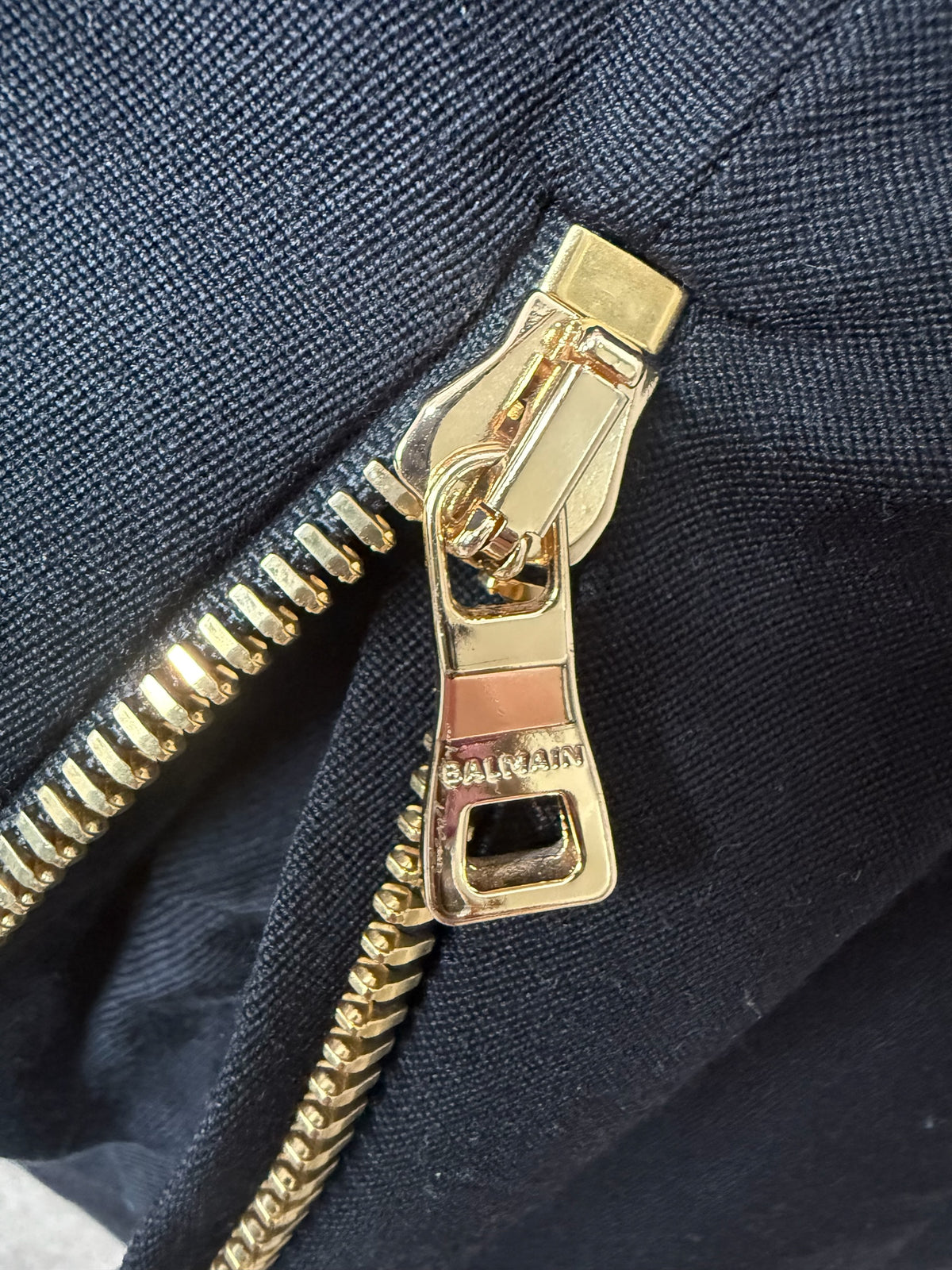 Style Reset Balmain black mini dress featuring a polished gold-tone metal zip pull with engraved logo detail