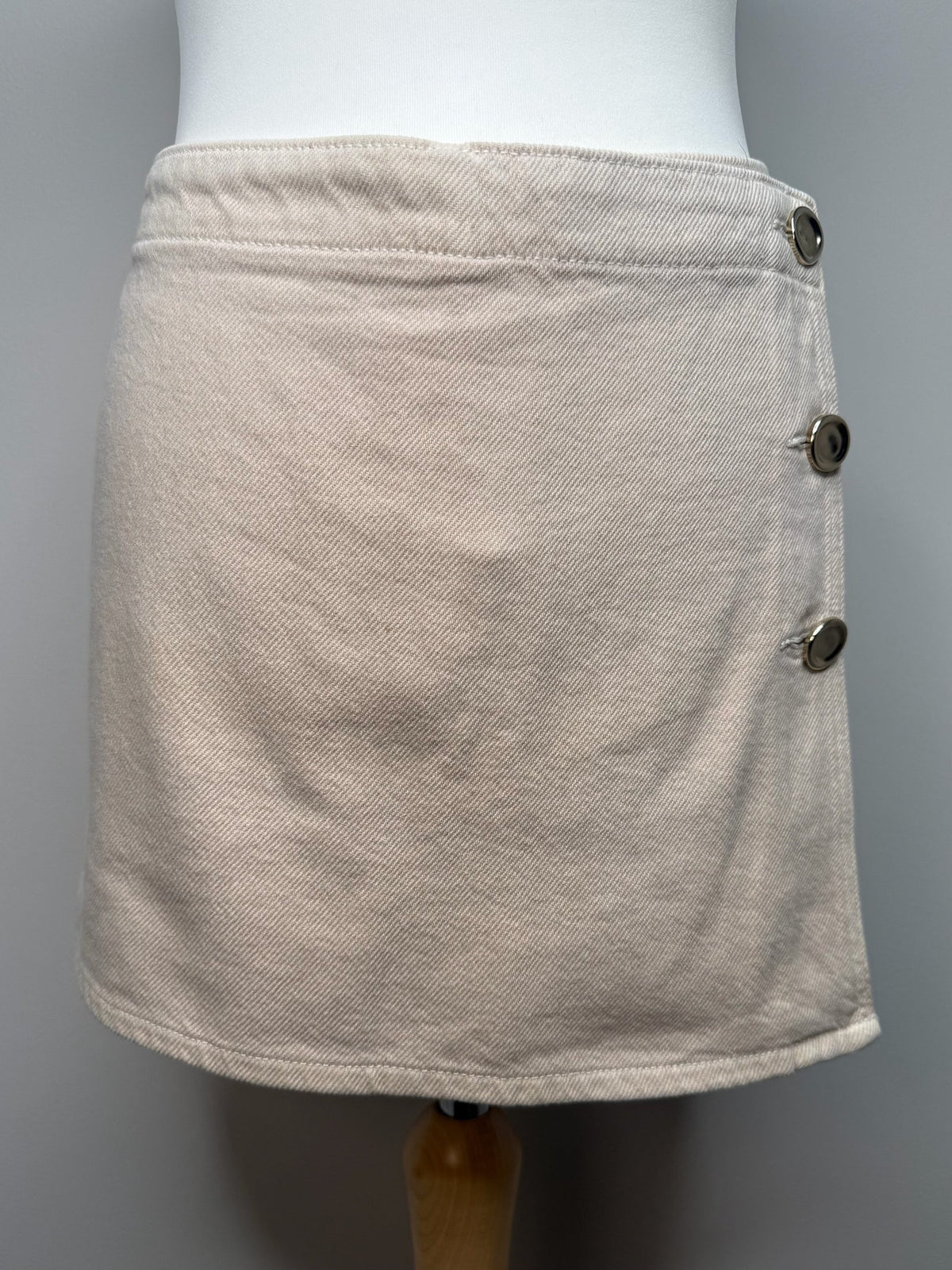 Style Reset beige denim mini skirt with side button detailing on a mannequin