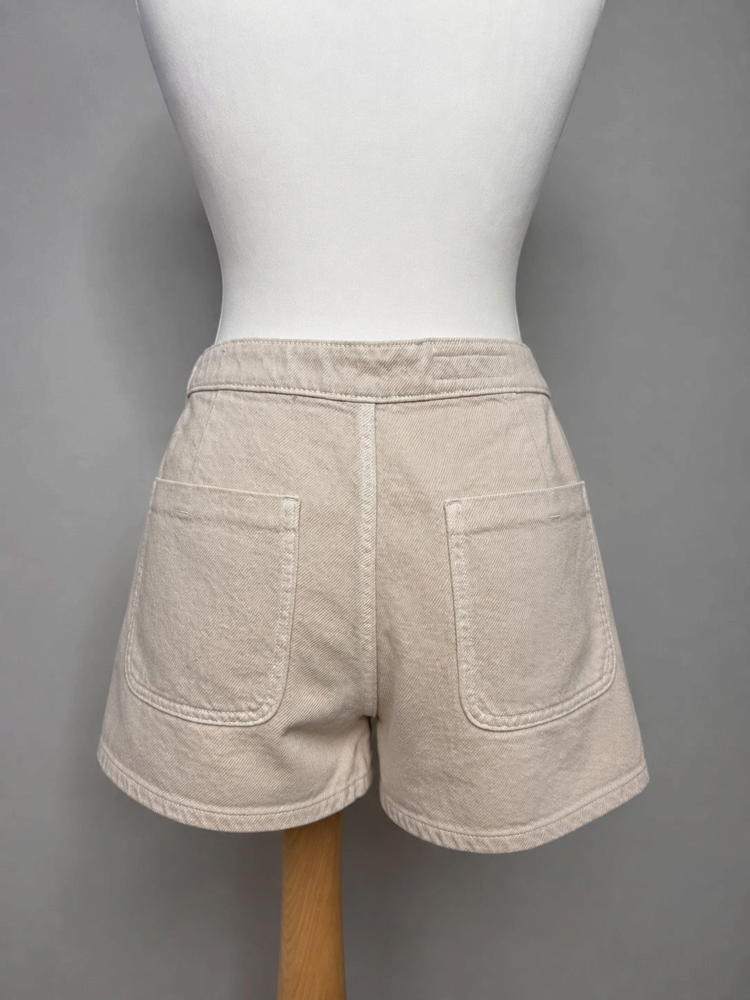 Style Reset beige cotton denim shorts featuring a structured fit and functional back pockets on a mannequin