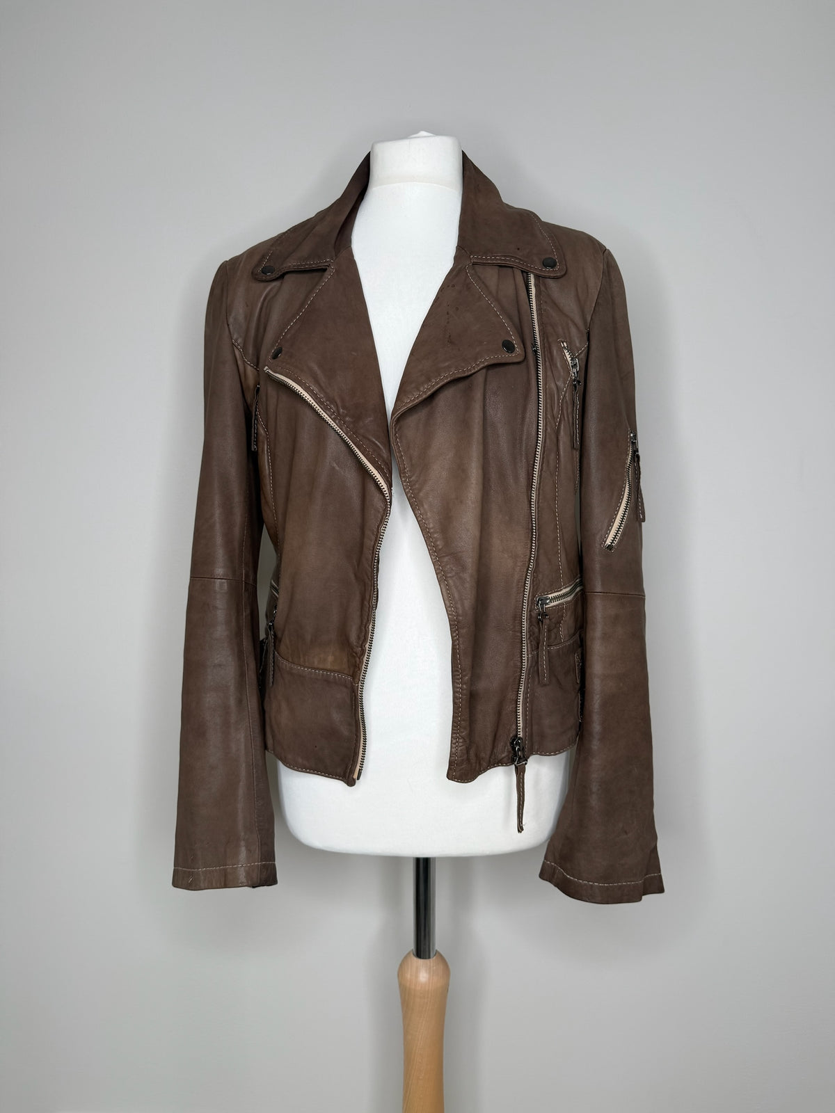 Style Reset brown leather biker jacket with asymmetric zip, notched lapels, and zipped pockets on a mannequin.