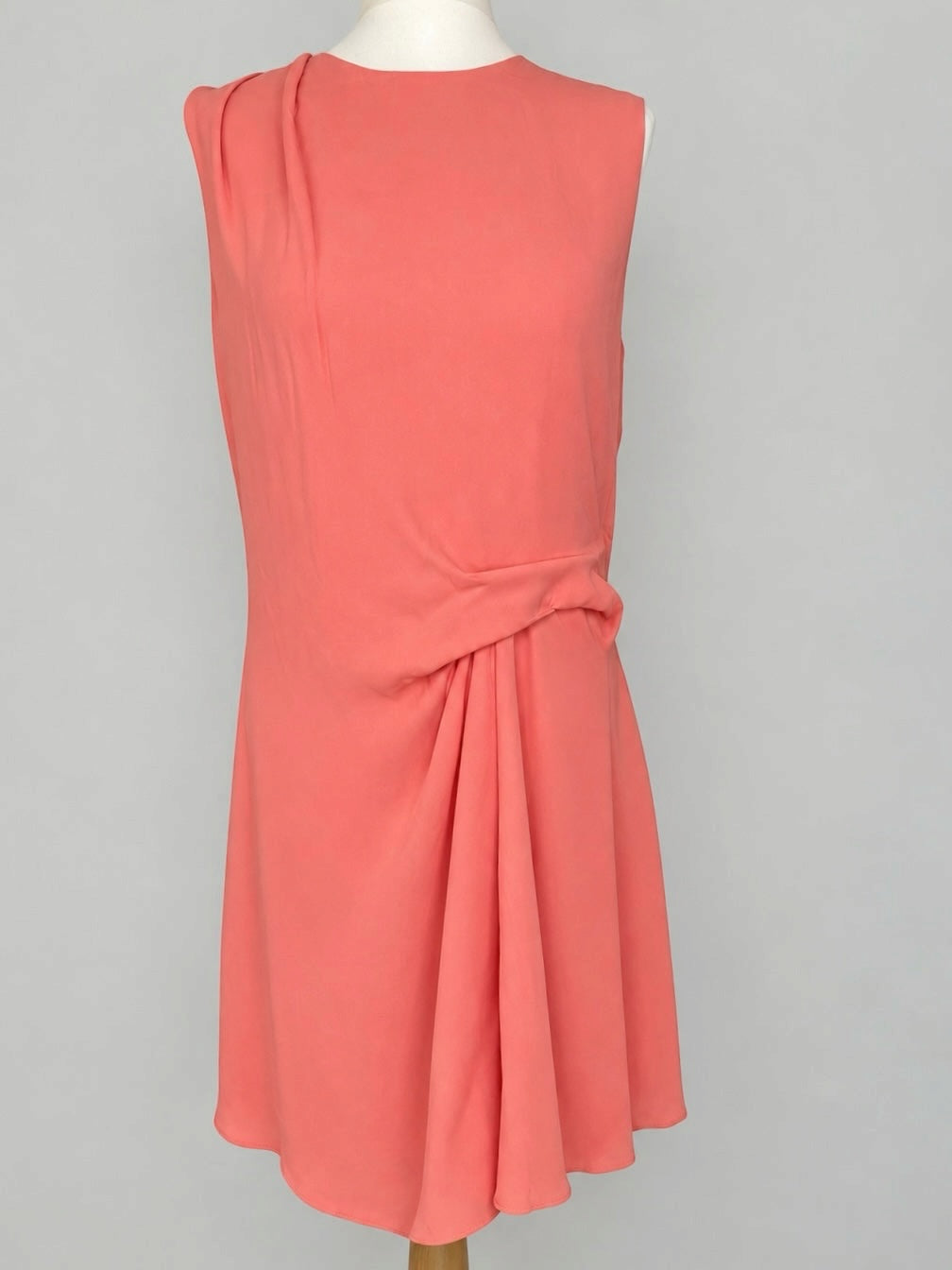 Style Reset coral sleeveless midi dress with elegant side-waist gathering and draped bodice detail on a mannequin