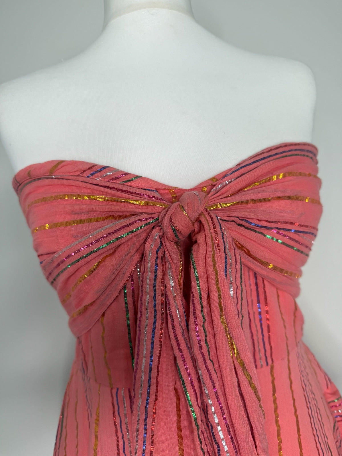 Style Reset strapless coral maxi dress featuring a knotted front, shirred bodice, and shimmering metallic stripes.