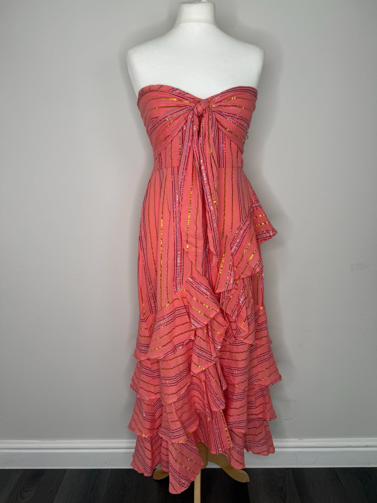Style Reset coral strapless maxi dress with metallic stripes, shirred bodice, knotted front, and cascading ruffles.