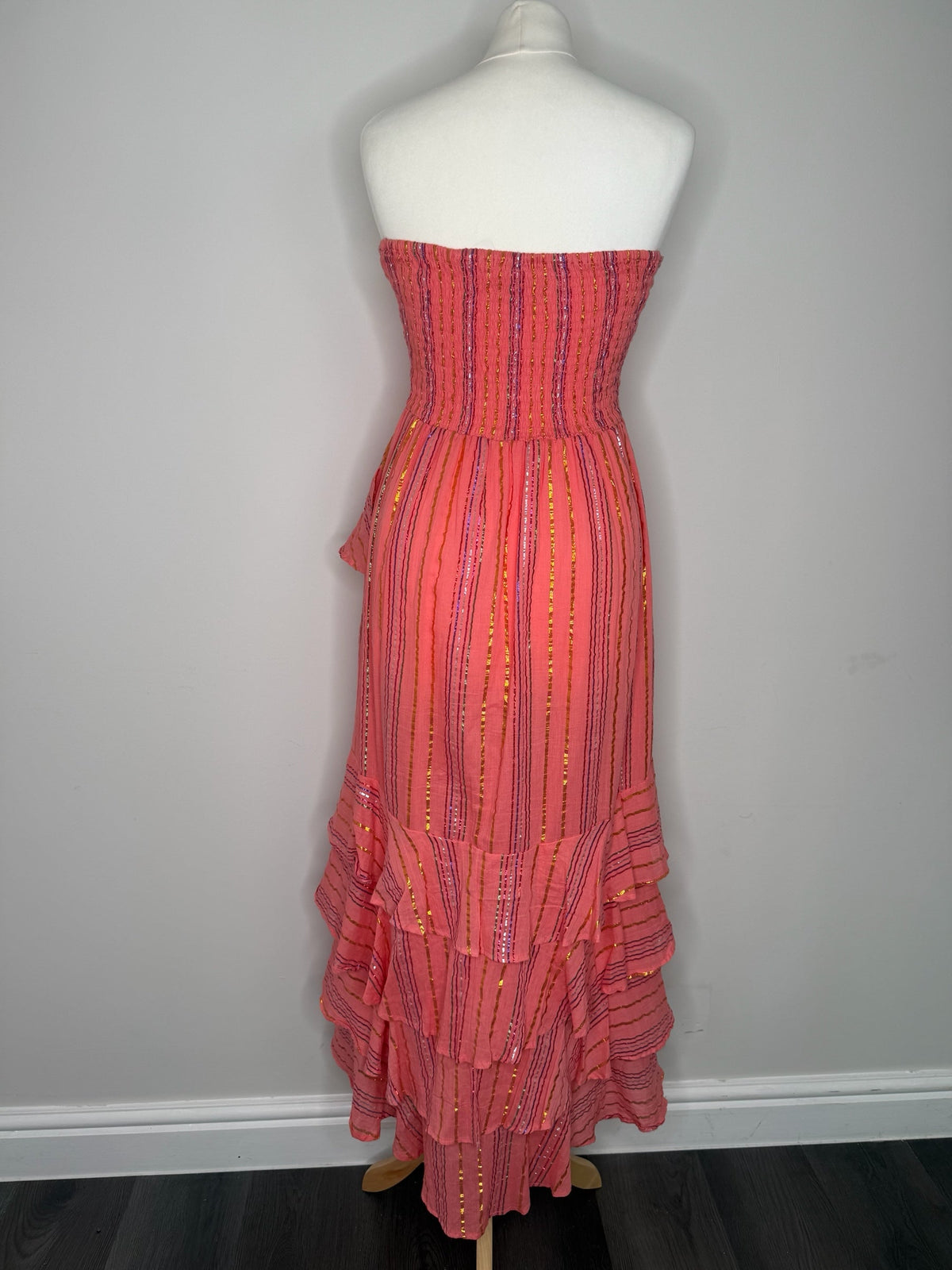 Style Reset coral strapless maxi dress with metallic stripes, shirred bodice, and cascading ruffle skirt on mannequin