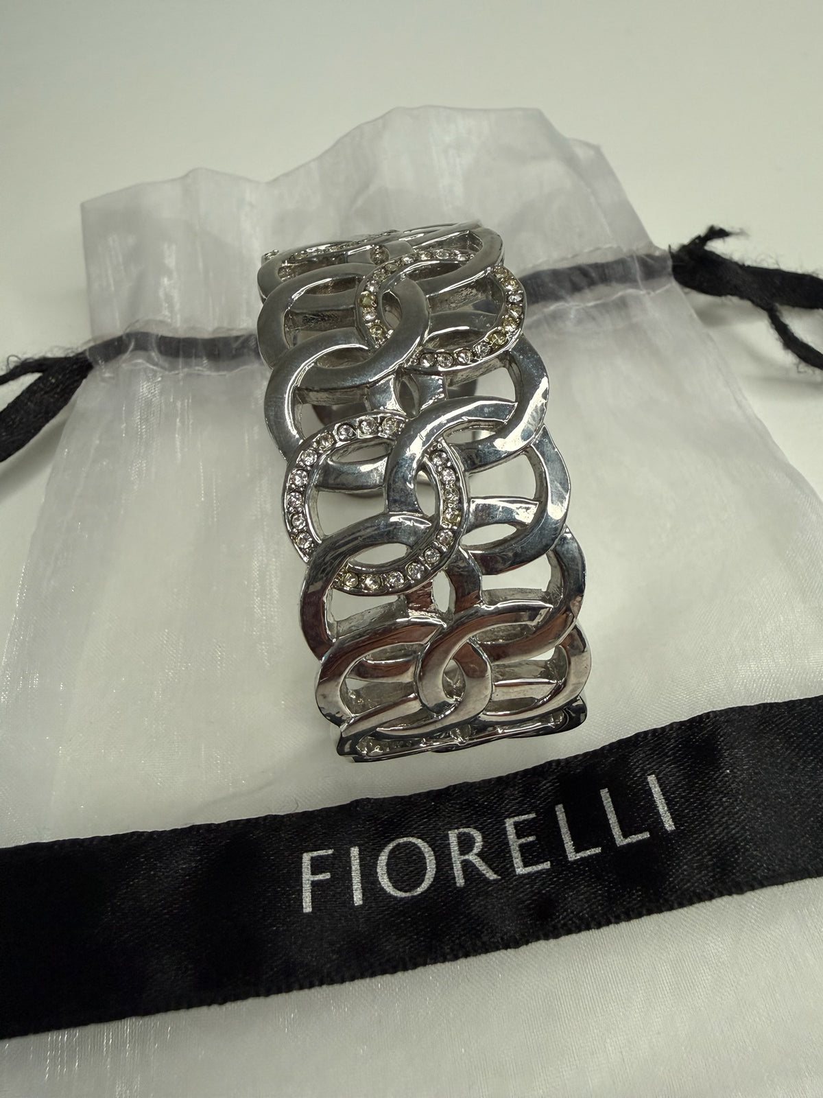 Style Reset Fiorelli silver-tone wide cuff bracelet with interlocking circular links and clear crystal embellishments.