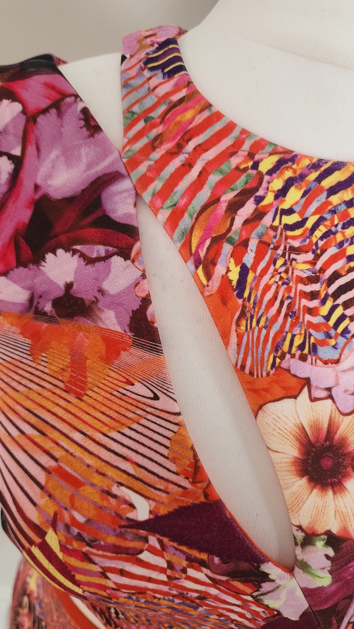 Style Reset sleeveless mini dress featuring a vibrant abstract floral print in orange, pink, and purple with cut-outs.