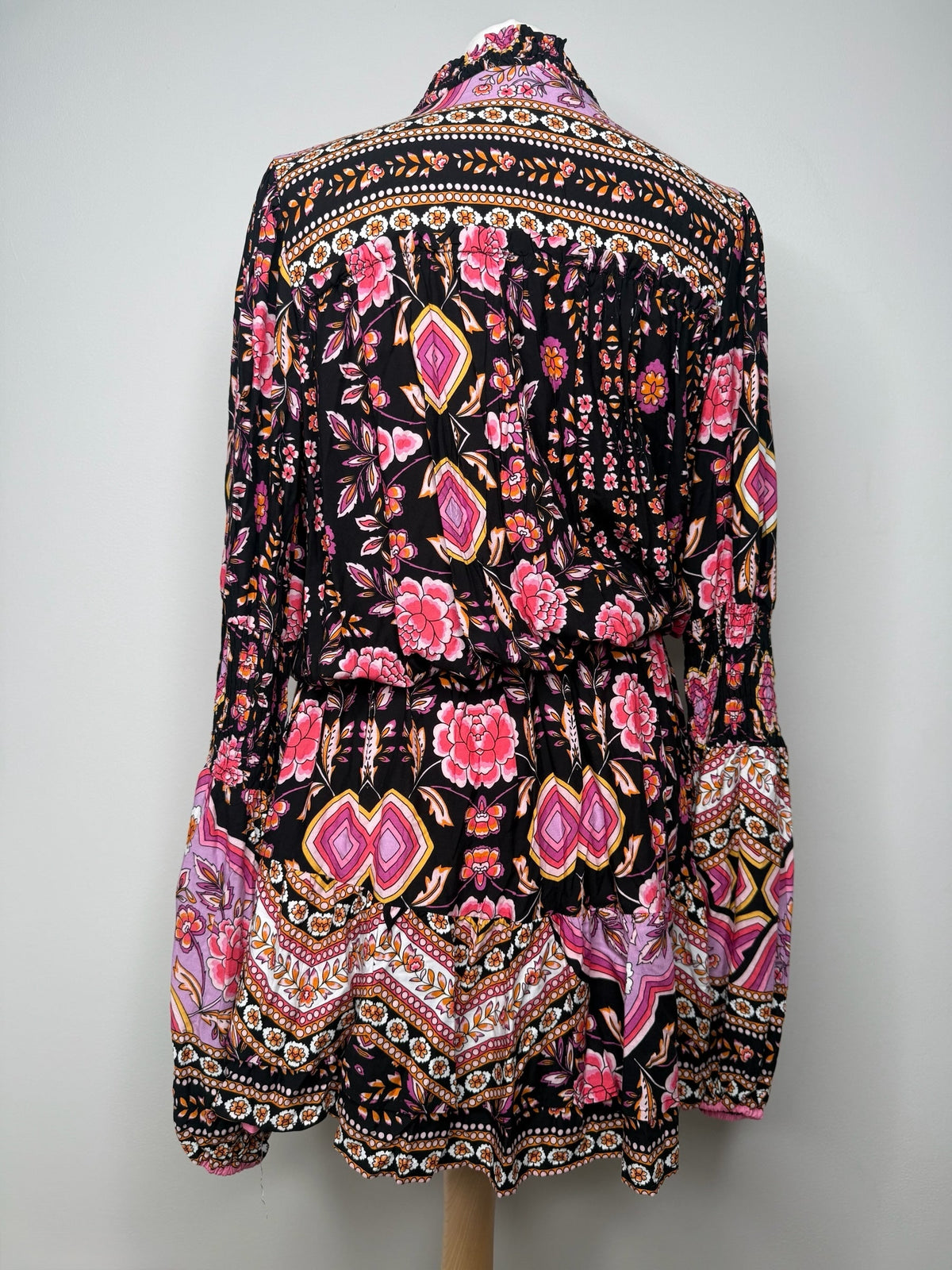 Style Reset bohemian mini dress with black base, vibrant floral and geometric print, ruffled collar, and long sleeves.