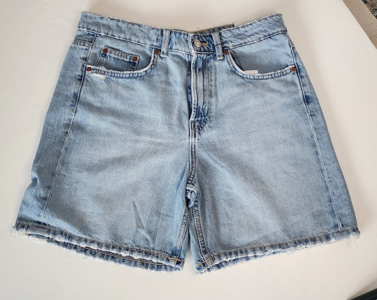 Style Reset light wash denim Bermuda shorts with a high-rise waist and raw frayed hemline on a white background.