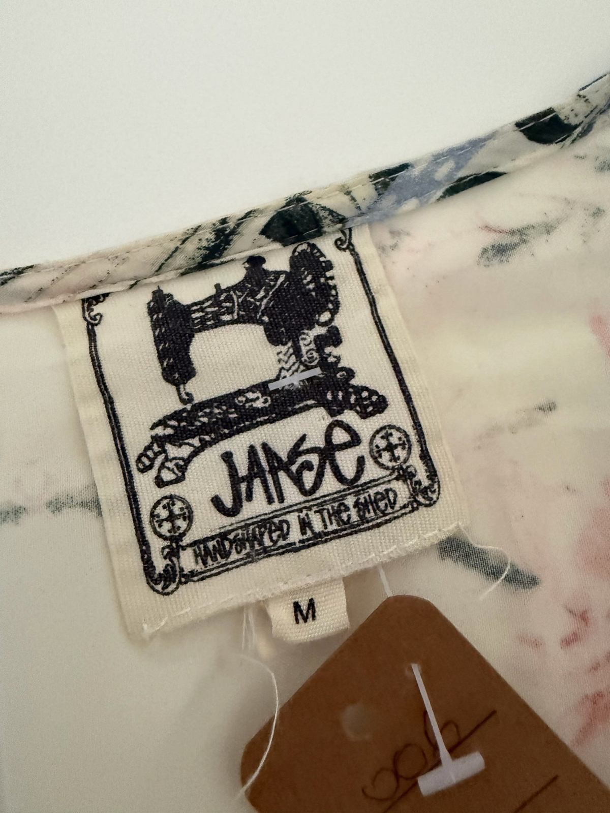 Style Reset JANE Handshaped In The Shed dress label with sewing machine logo and size M tag on floral fabric