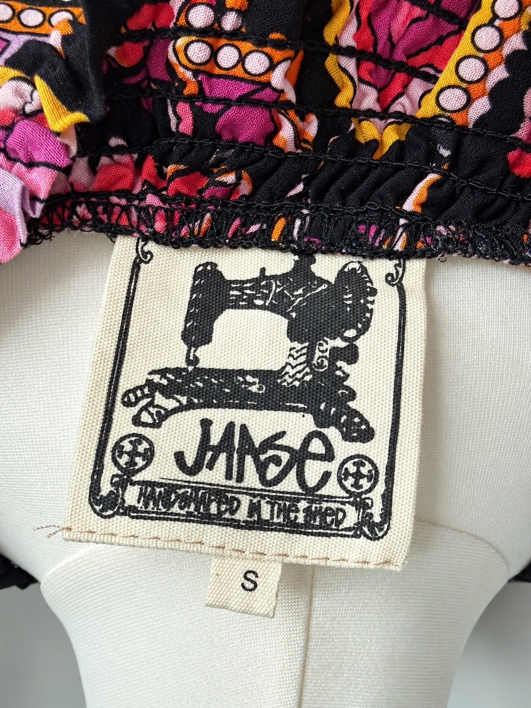 Style Reset JANSE hand-made mini dress label showing sewing machine logo on vibrant floral print fabric