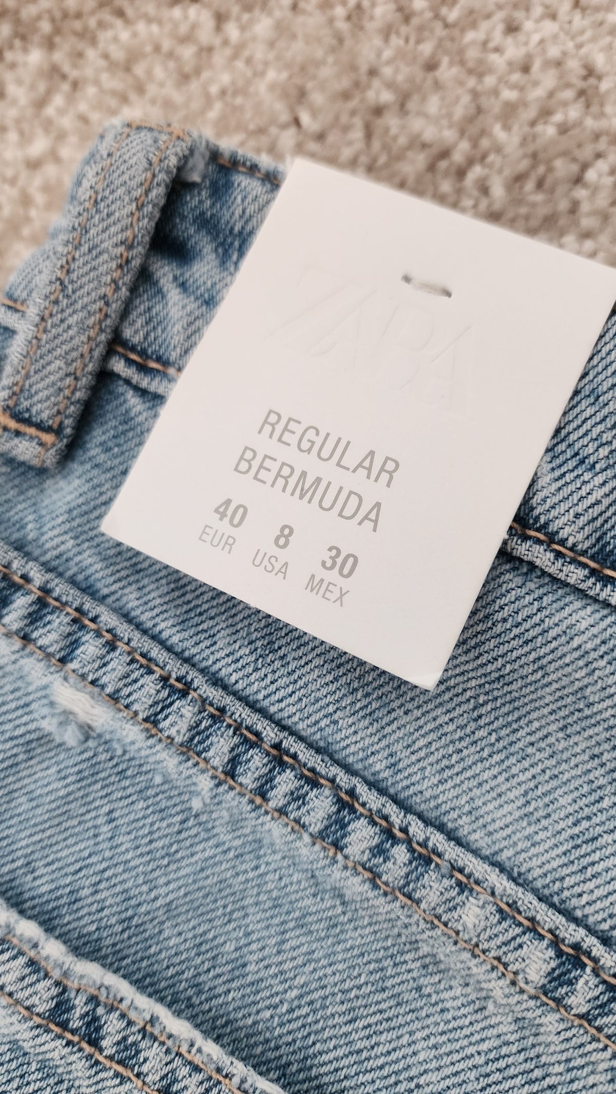 Style Reset light-wash blue denim Bermuda shorts with a white retail tag showing sizing details