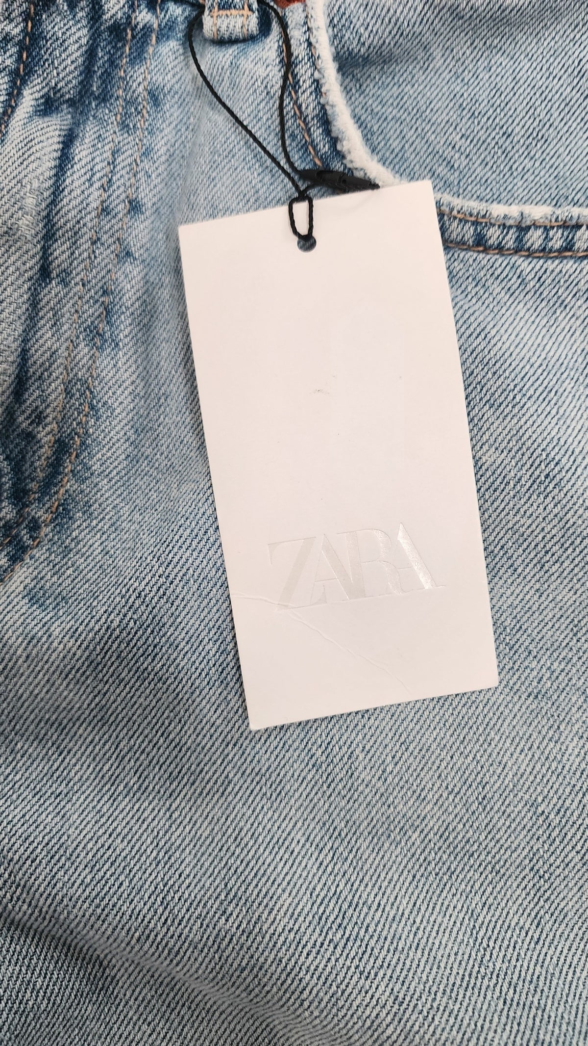 Style Reset light wash denim Bermuda shorts with a raw hem and a white brand tag attached