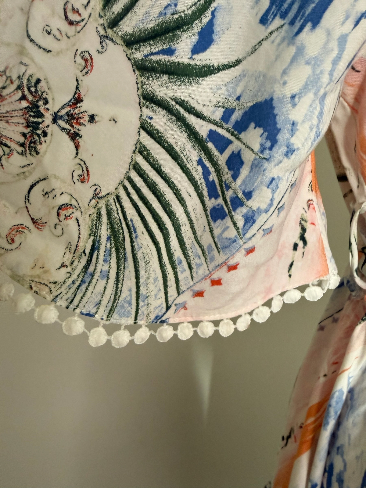 Style Reset midi dress sleeve detail featuring a vibrant botanical print in pink, blue, and green with pom-pom trim.