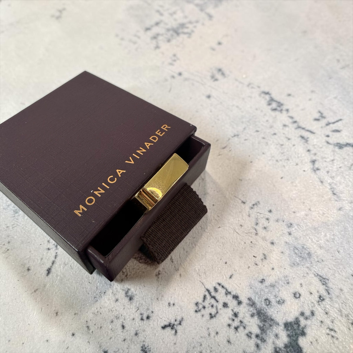Style Reset Monica Vinader gold-tone designer ring inside its signature dark brown branded presentation box