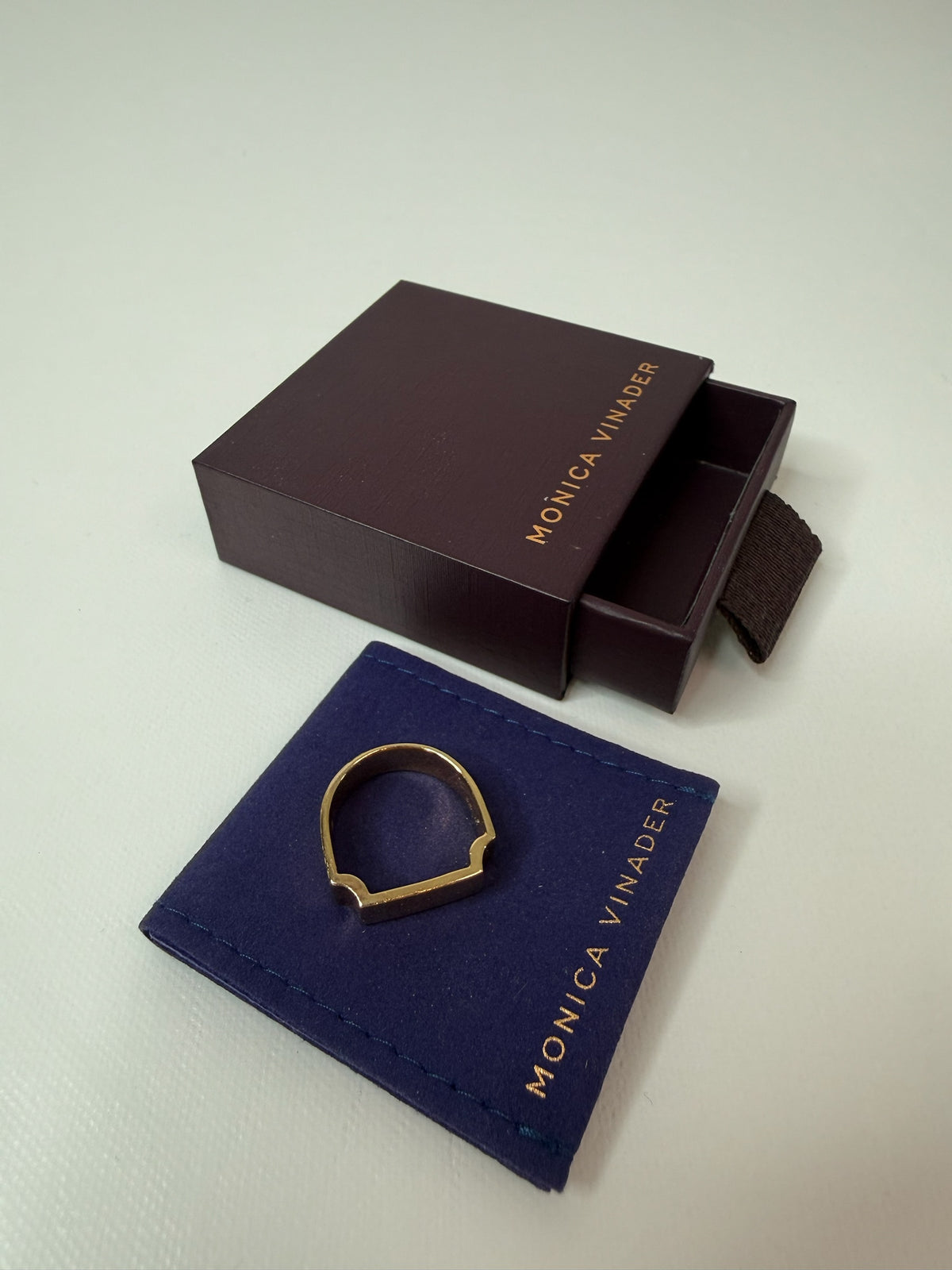 Style Reset gold-tone Monica Vinader architectural signet ring displayed on a blue velvet pouch with a branded box.