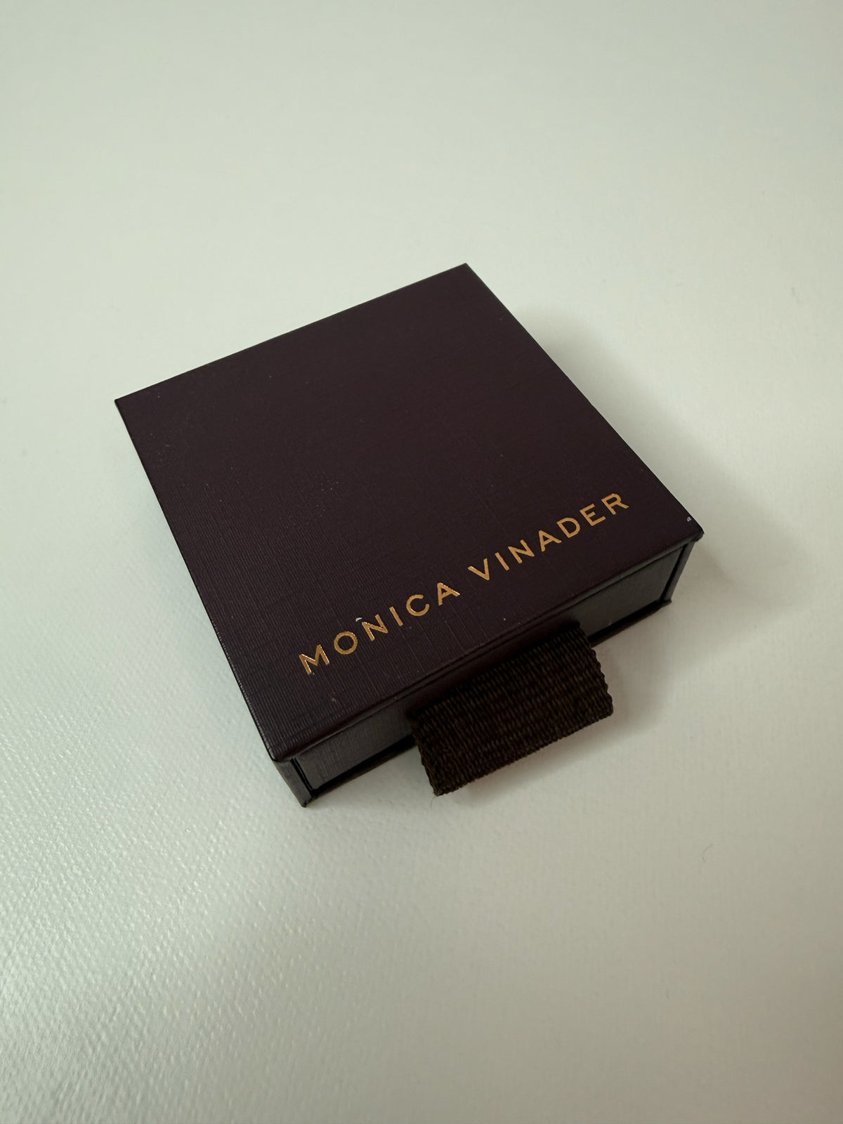 Style Reset branded Monica Vinader jewellery box in dark brown with gold lettering on a white surface
