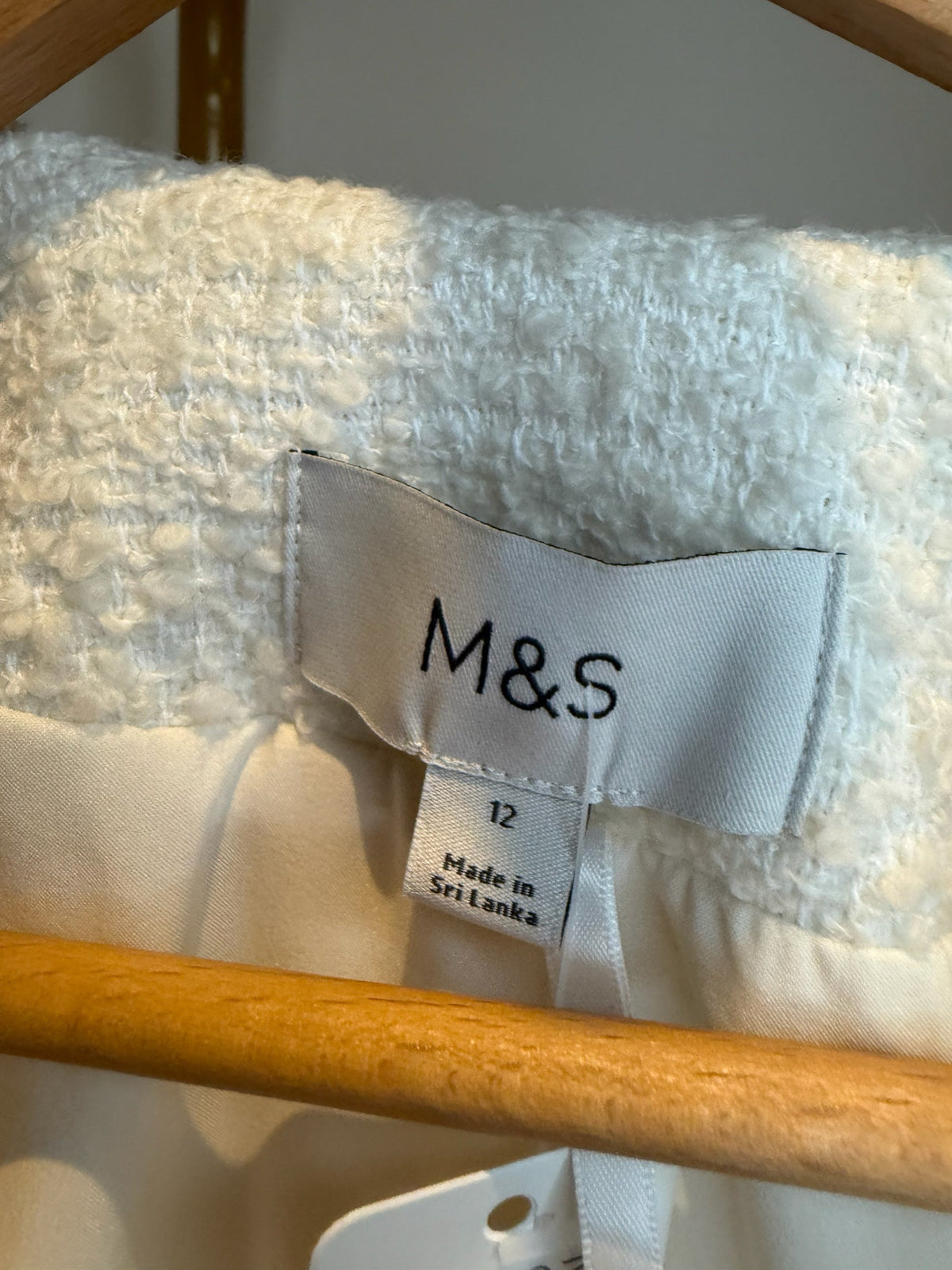 Style Reset M&S cream textured boucle jacket label showing size 12 and origin on a wooden hanger