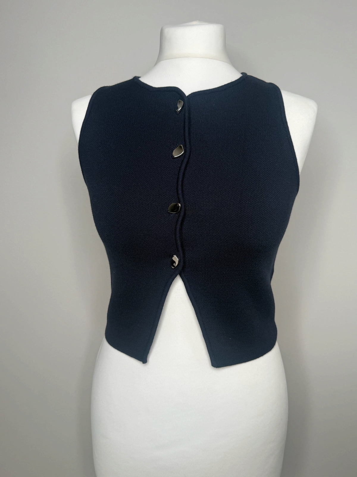 Style Reset navy blue sleeveless knit top with a front button-down design and metallic hardware on a mannequin