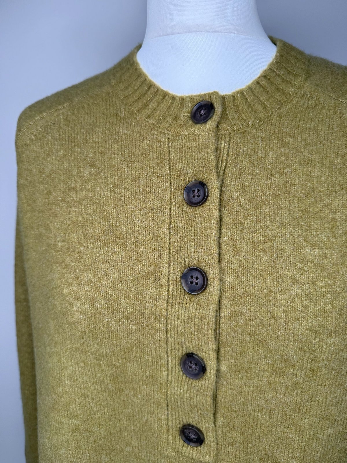 Style Reset olive green knit jumper with a crew neckline and a functional button-down placket on a mannequin