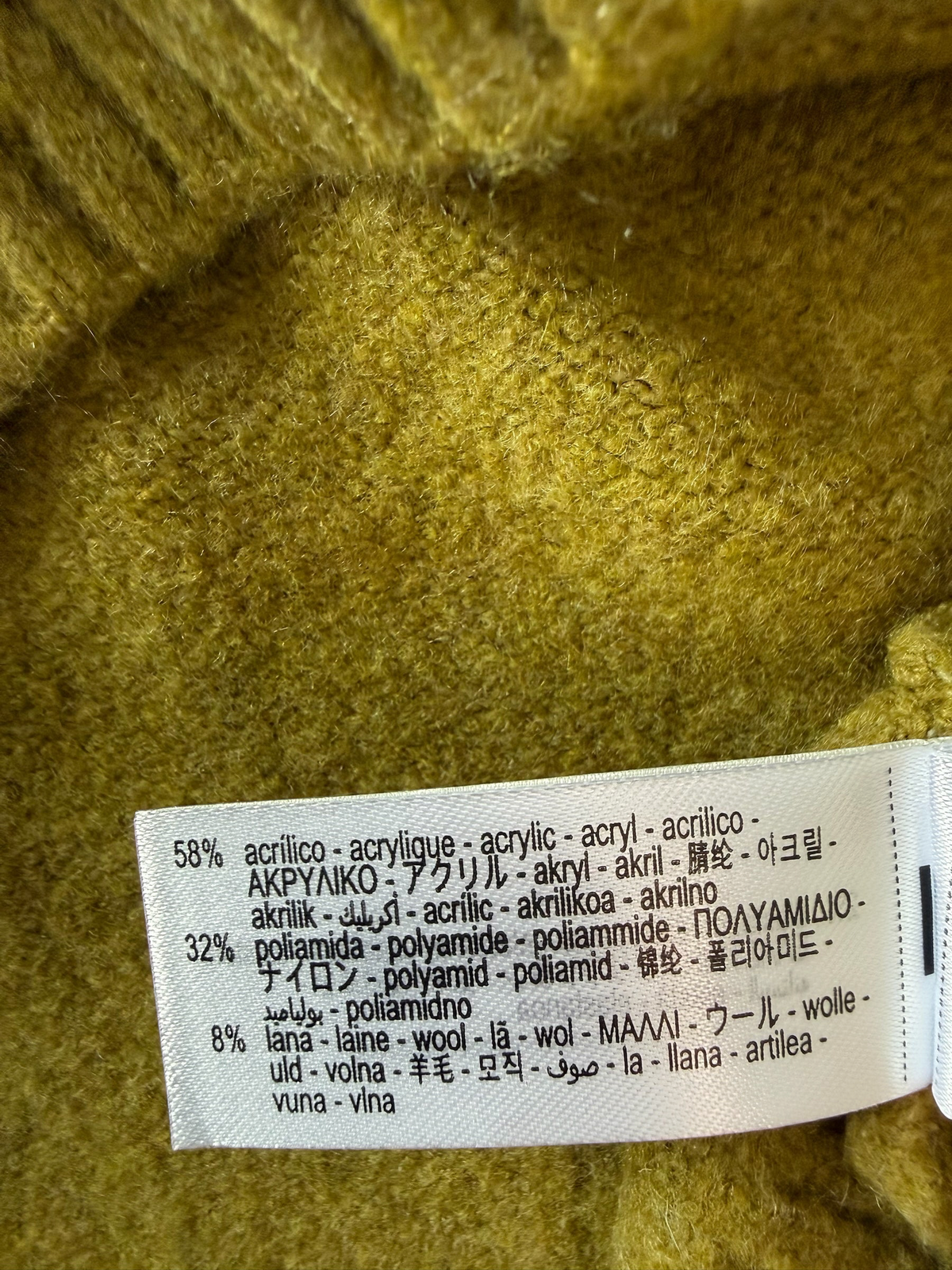 Style Reset olive knit sweater fabric care label showing material composition of acrylic, polyamide, and wool blend
