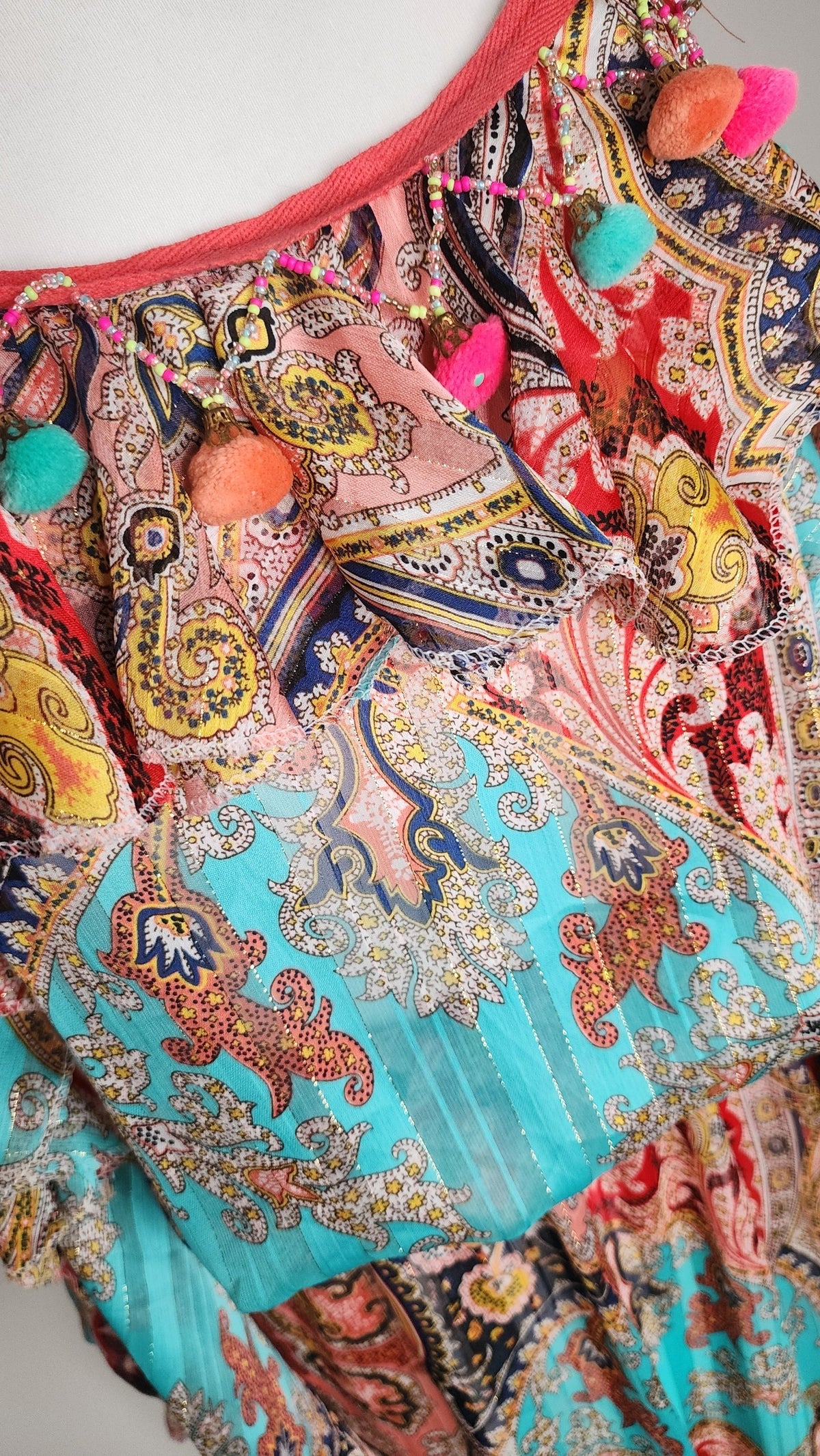 Style Reset paisley print summer dress featuring a ruffled overlay, turquoise and coral tones, and pom-pom trim.