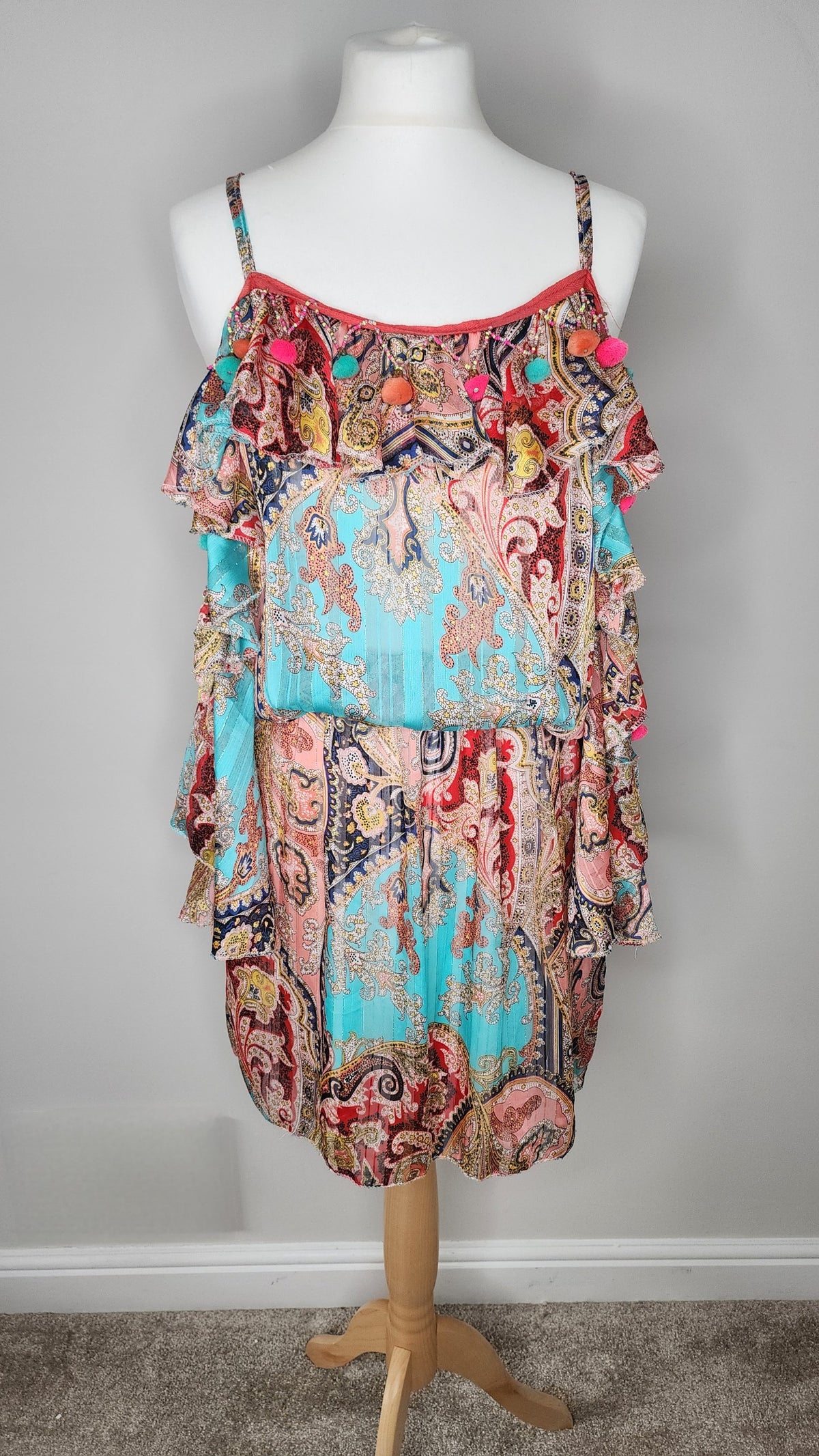 Style Reset paisley print mini dress in turquoise and coral with ruffle overlay, spaghetti straps, and pom-pom trim.