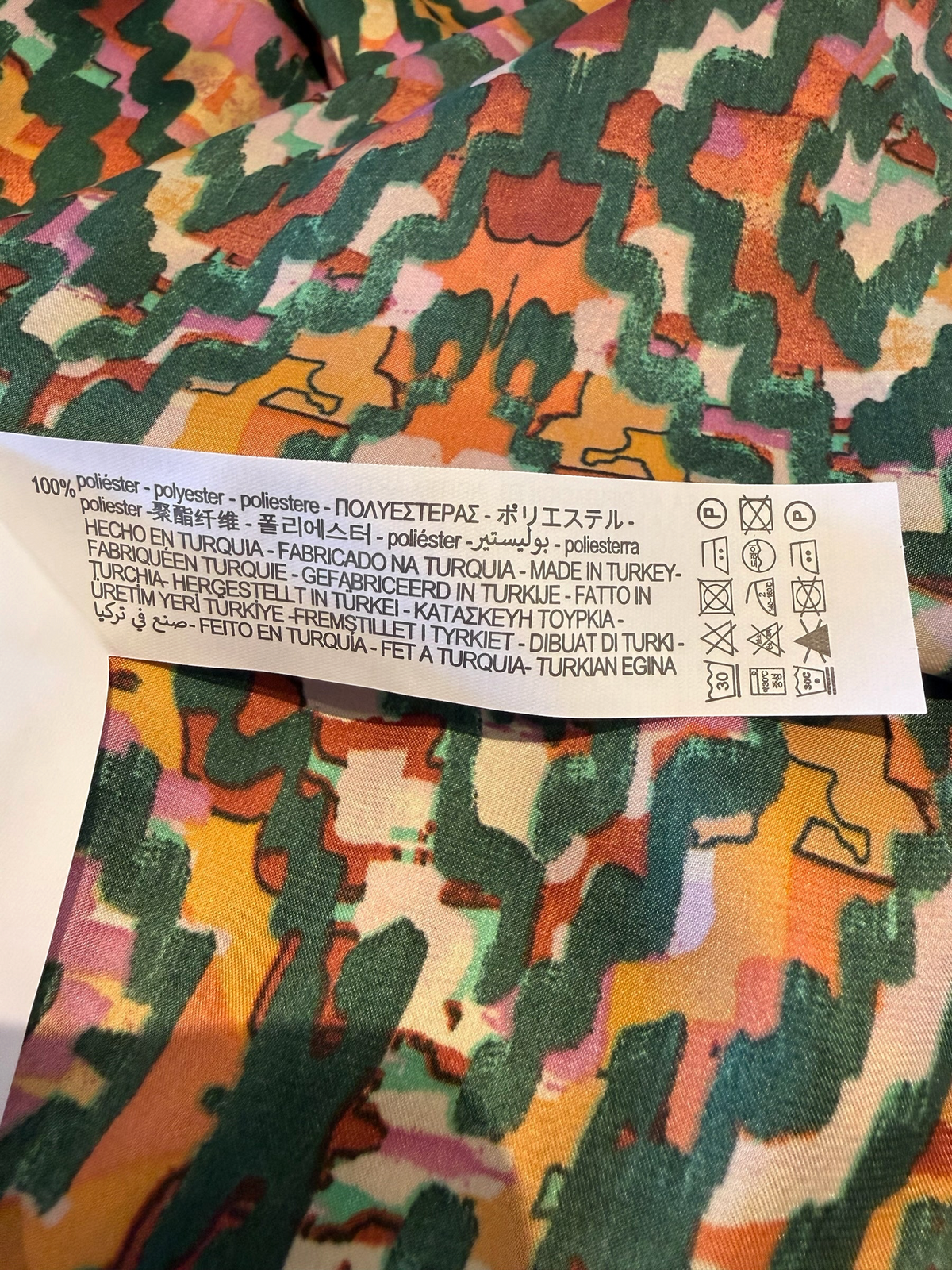 Style Reset maxi dress fabric label showing 100% polyester composition and care instructions on geometric print