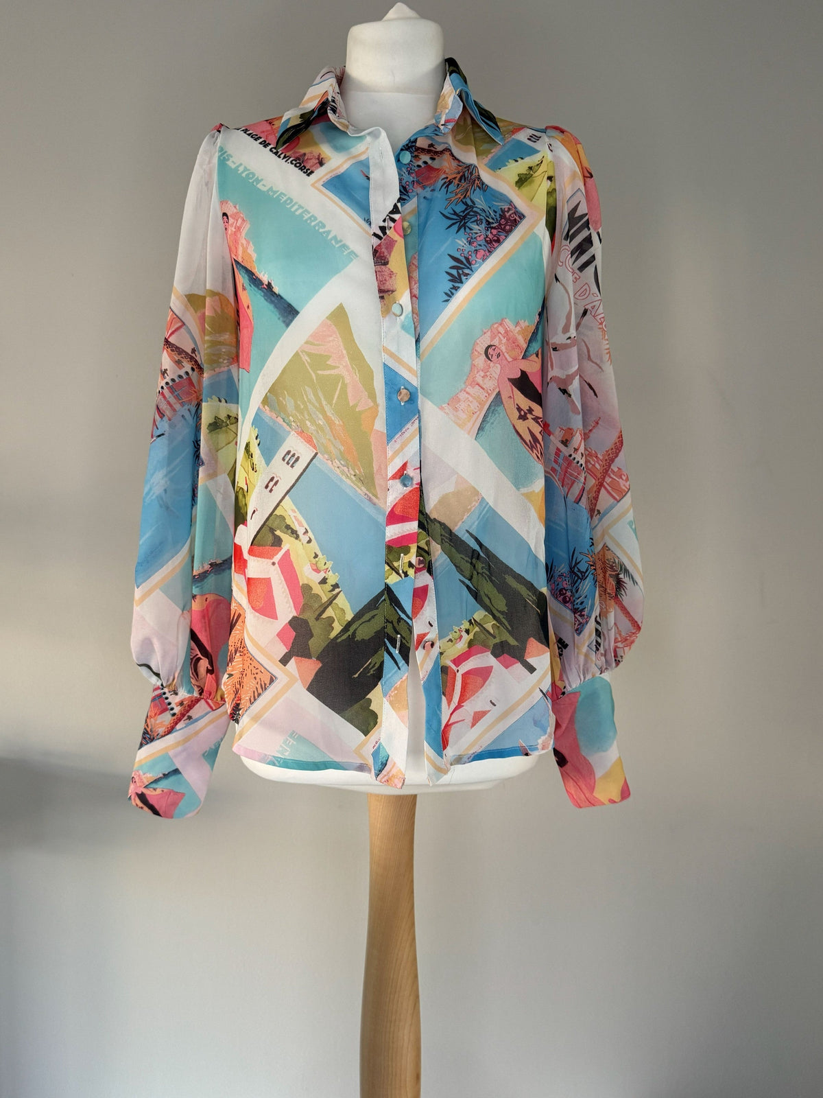 Style Reset long sleeve button-down blouse featuring a vibrant multi-colored Mediterranean postcard graphic print.
