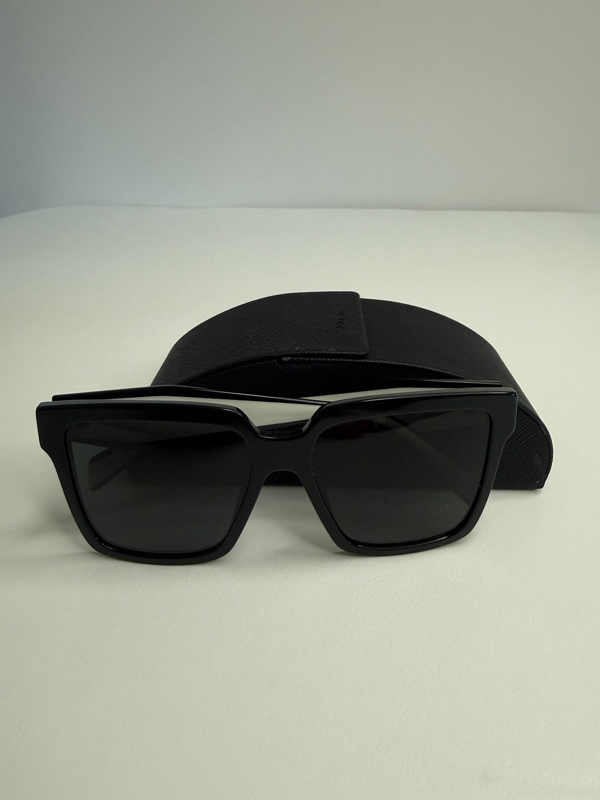 Style Reset Prada square frame black acetate sunglasses with matching Saffiano-textured protective case.
