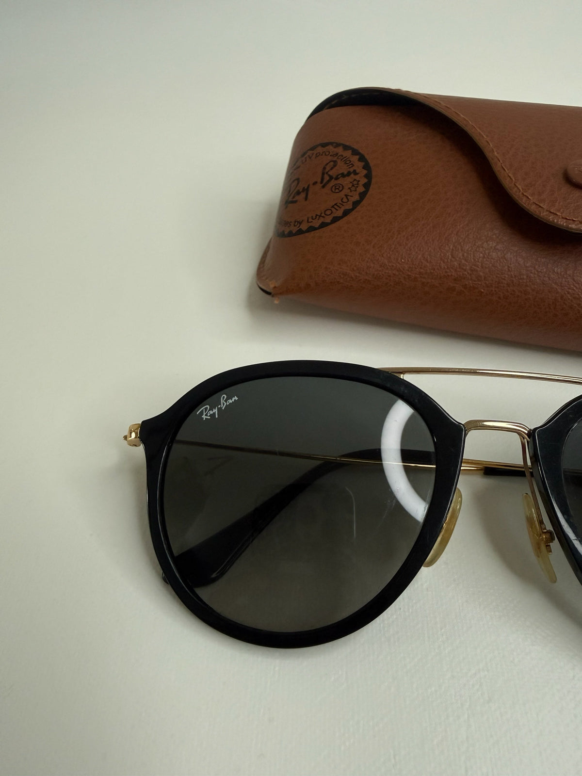 Style Reset Ray-Ban sunglasses with black frames, gold-tone double bridge, and a tan leather-look protective case.