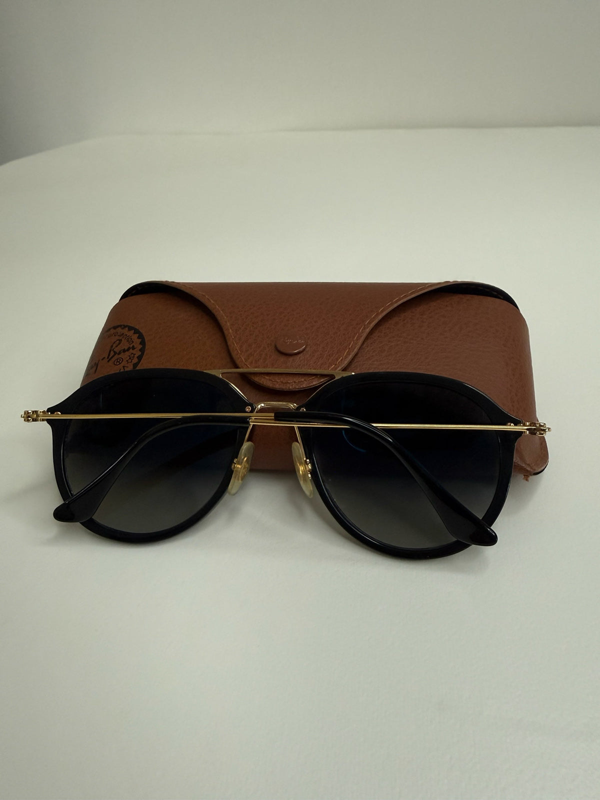 Style Reset Ray-Ban sunglasses with black frames, gold double-bridge, and tan leather-look protective case.