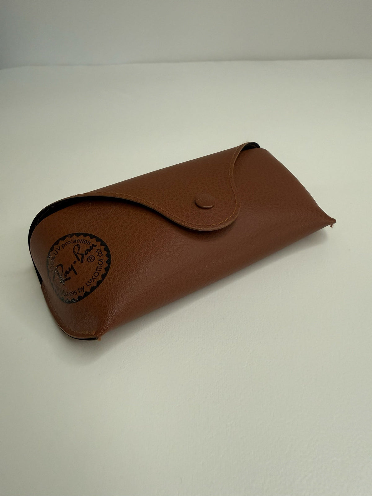 Style Reset tan leather-look protective case for Ray-Ban sunglasses with a snap button closure and brand logo