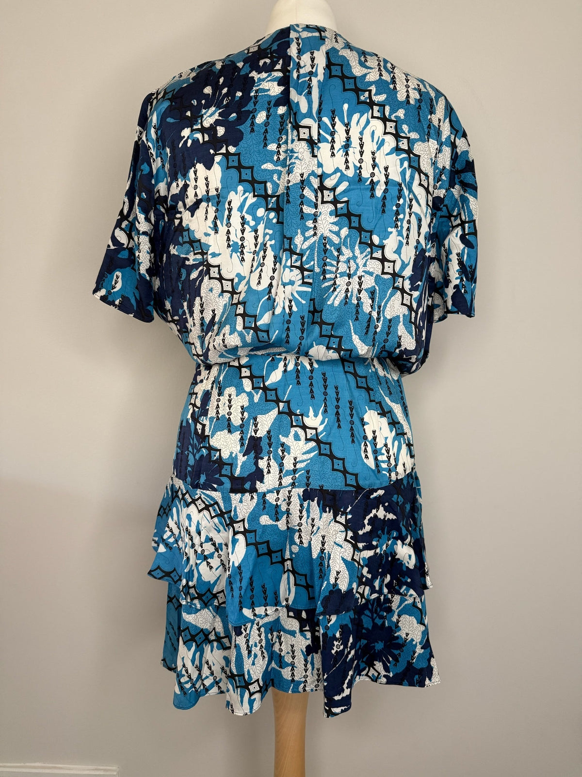Back view of a Style Reset REISS tiered mini dress in a blue, navy, and white geometric floral print with short sleeves