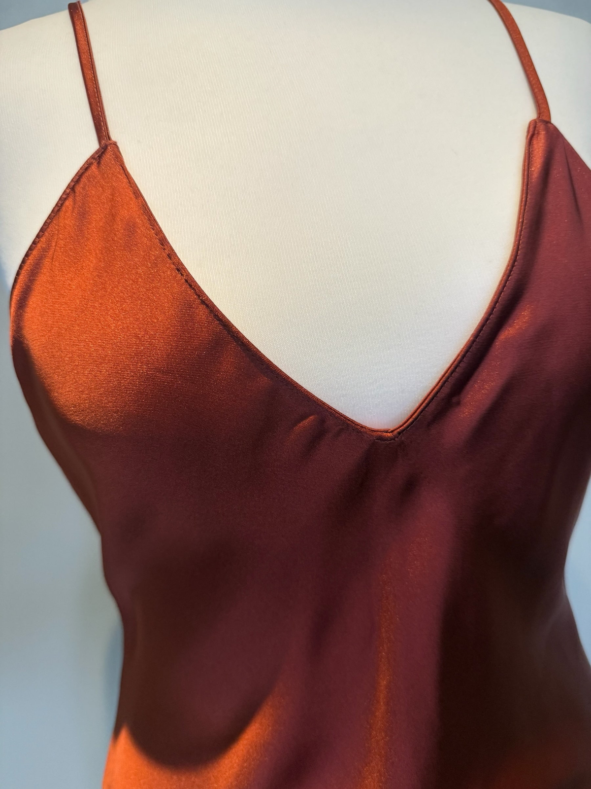 Style Reset rust-coloured satin slip dress with a V-neckline and delicate spaghetti straps on a mannequin