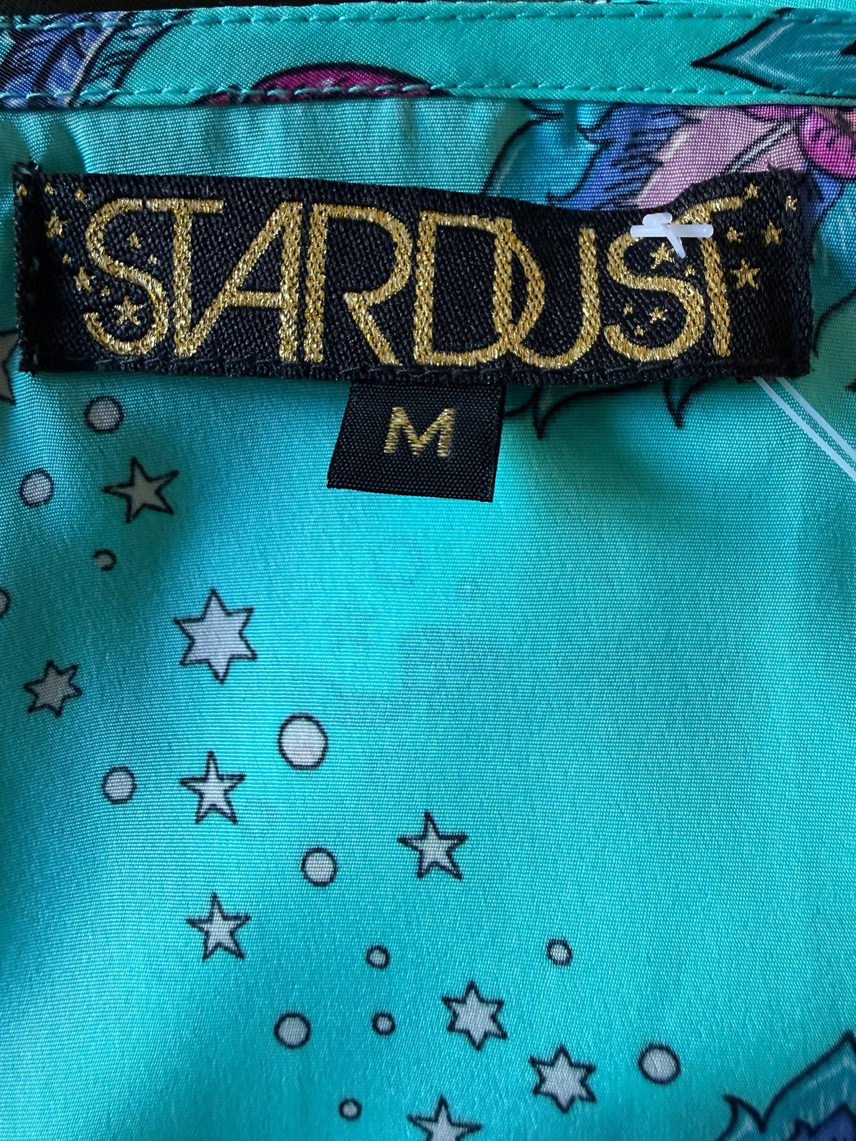 Style Reset STARDUST brand label on a turquoise silky dress with a whimsical star and hummingbird print