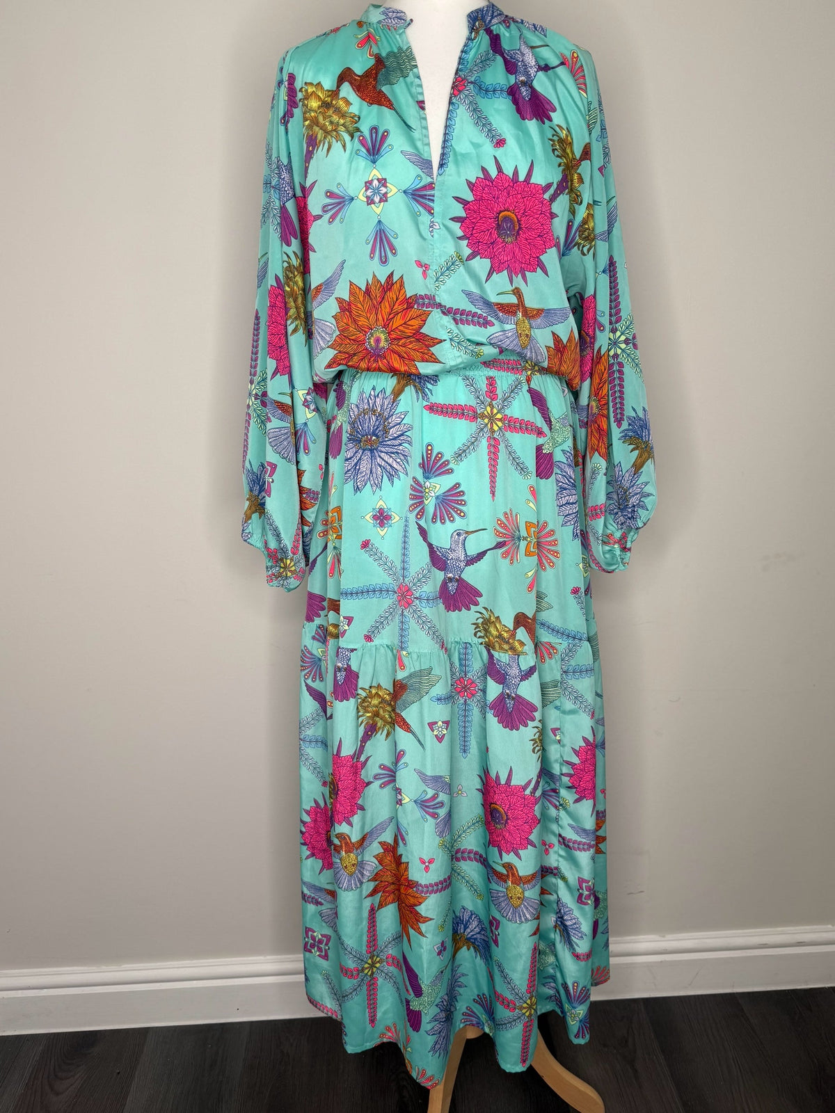 Style Reset turquoise maxi dress with long sleeves, V-neckline, and vibrant hummingbird and floral print on mannequin.