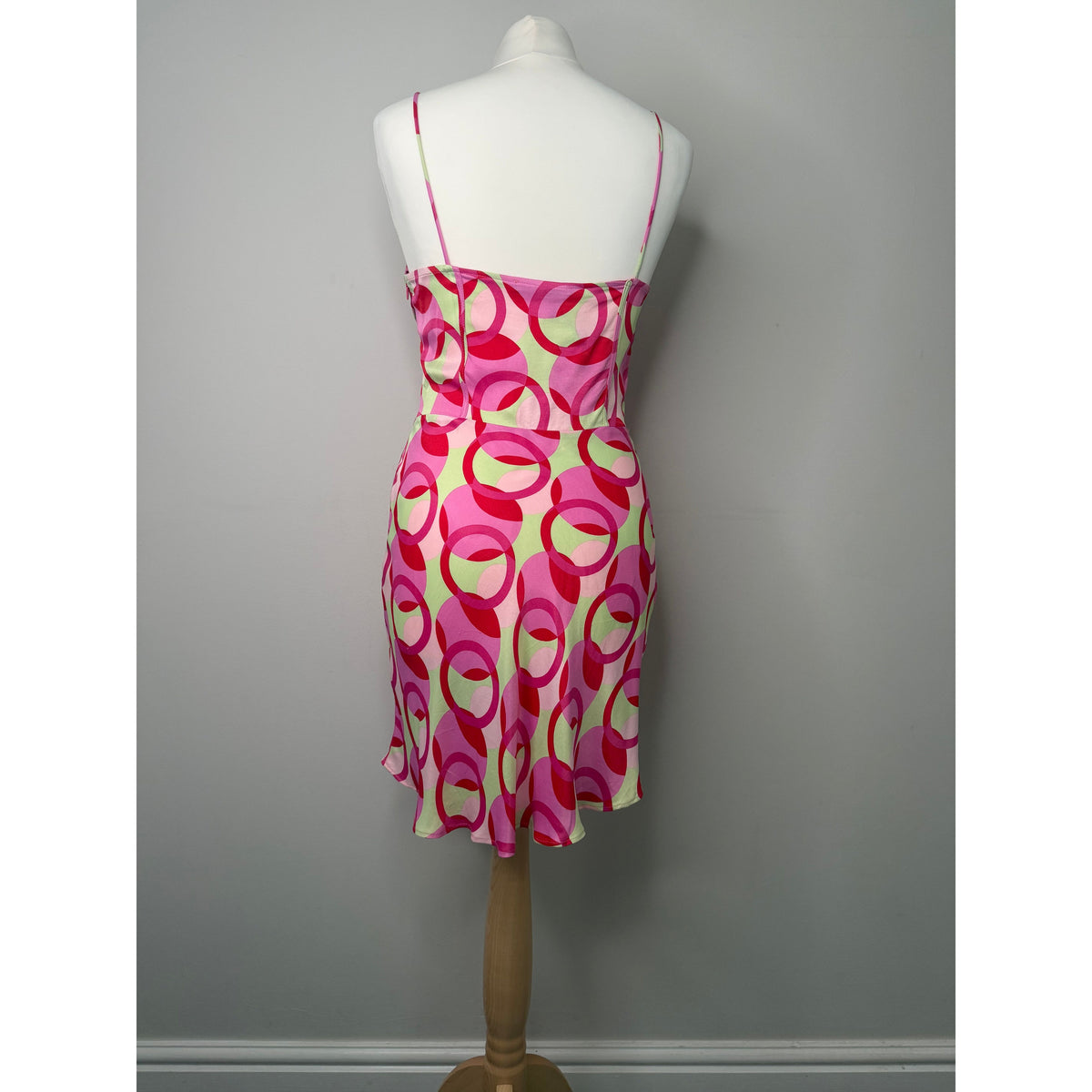 Style Reset Zara mini dress in pink and sage green geometric circle print on a mannequin, back view.